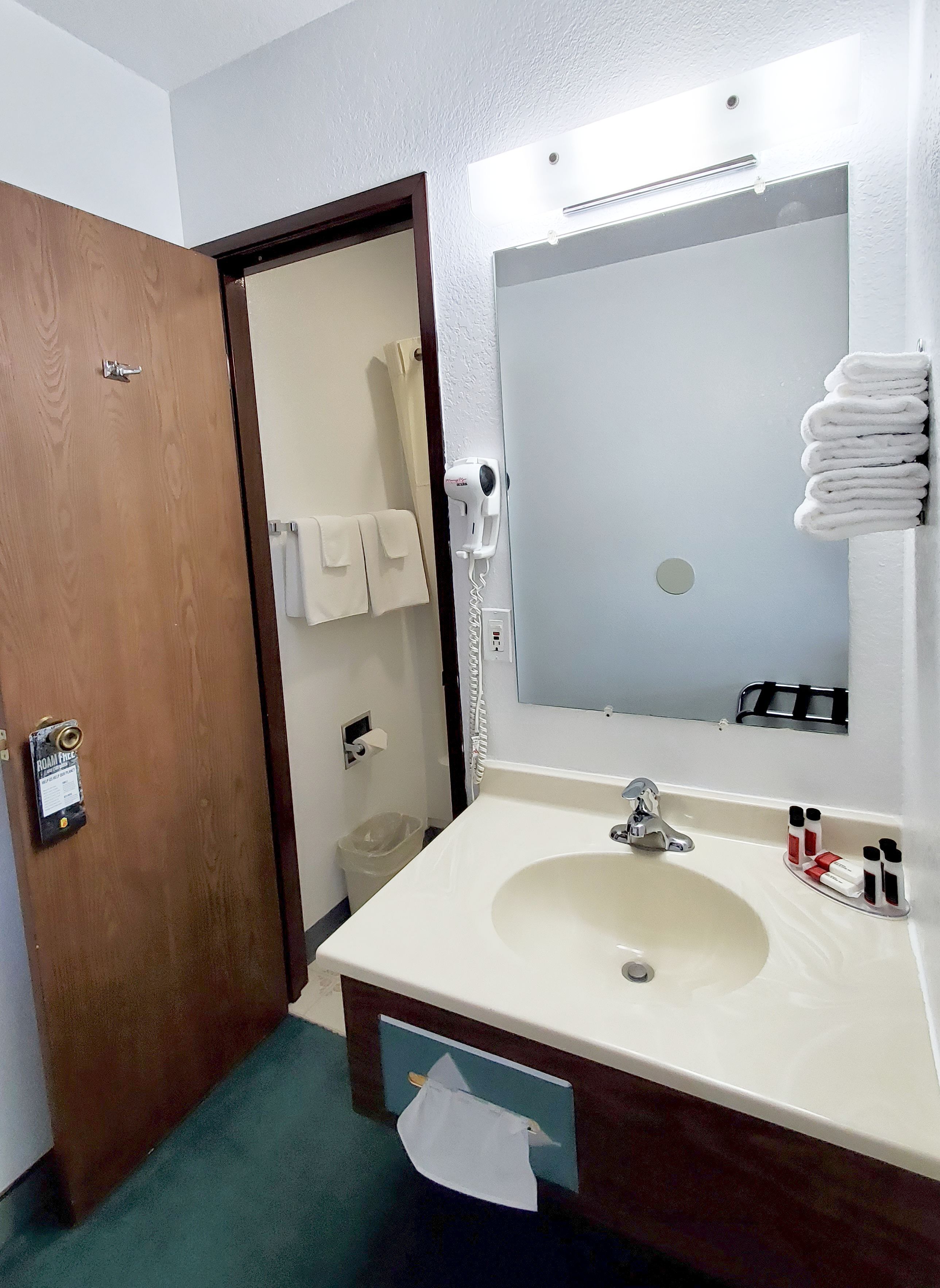 A hotel bathroom with a sink, mirror, and towel rack.