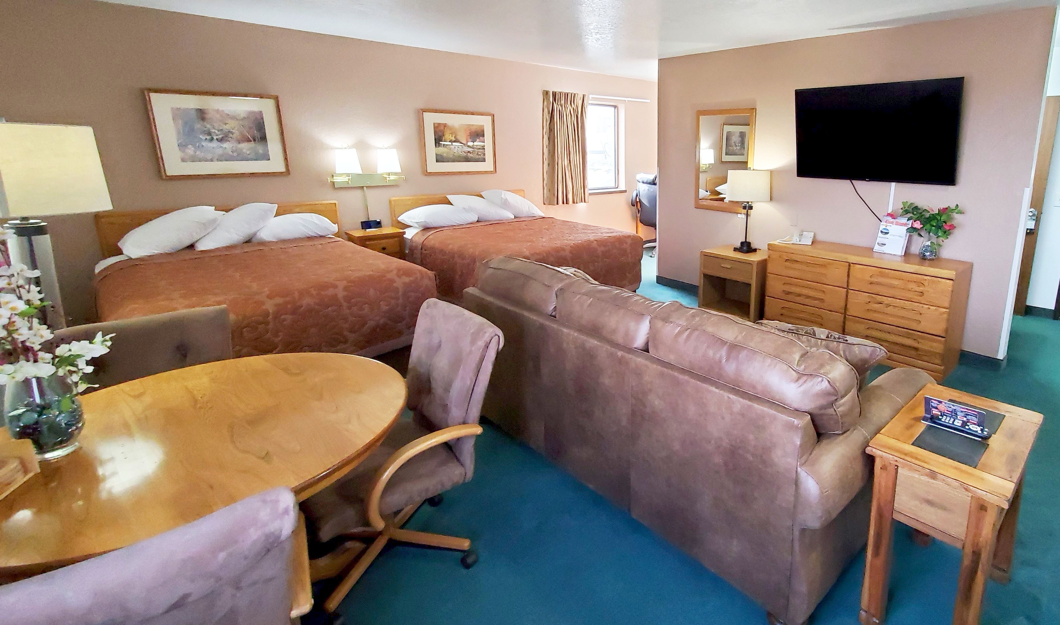 Una habitación de hotel con dos camas, un sofá, un escritorio, un televisor y un aparador.