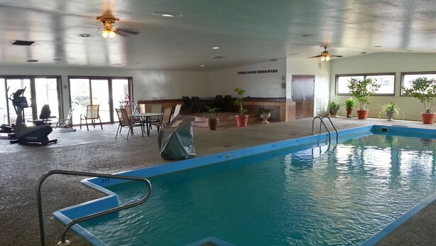 An indoor swimming pool with a 3FT depth marker, surrounded by exercise equipment, seating, and potted plants. - Super 8 by Wyndham Cut Bank (Cut Bank)