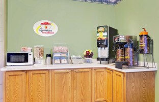 Una barra de desayuno con microondas, cafetera y dispensadores de bebidas.