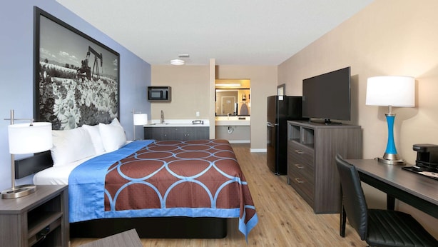 A hotel room with a bed, desk, TV, and a bathroom visible through an open door. - Super 8 by Wyndham Victoria / South / Hwy 59 (Victoria)