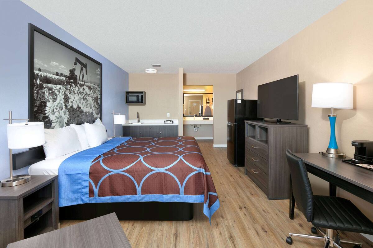 A hotel room with a bed, desk, TV, and a bathroom visible through an open door.
