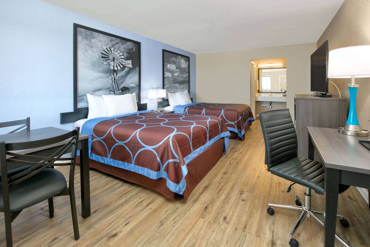 A hotel room with a large bed, a desk, a chair, and a television.