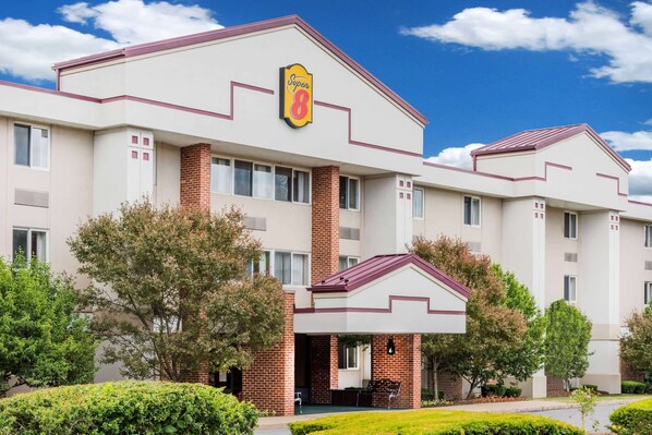 Distinctive hotel with a symmetrical design and central entrance, set amidst lush greenery.