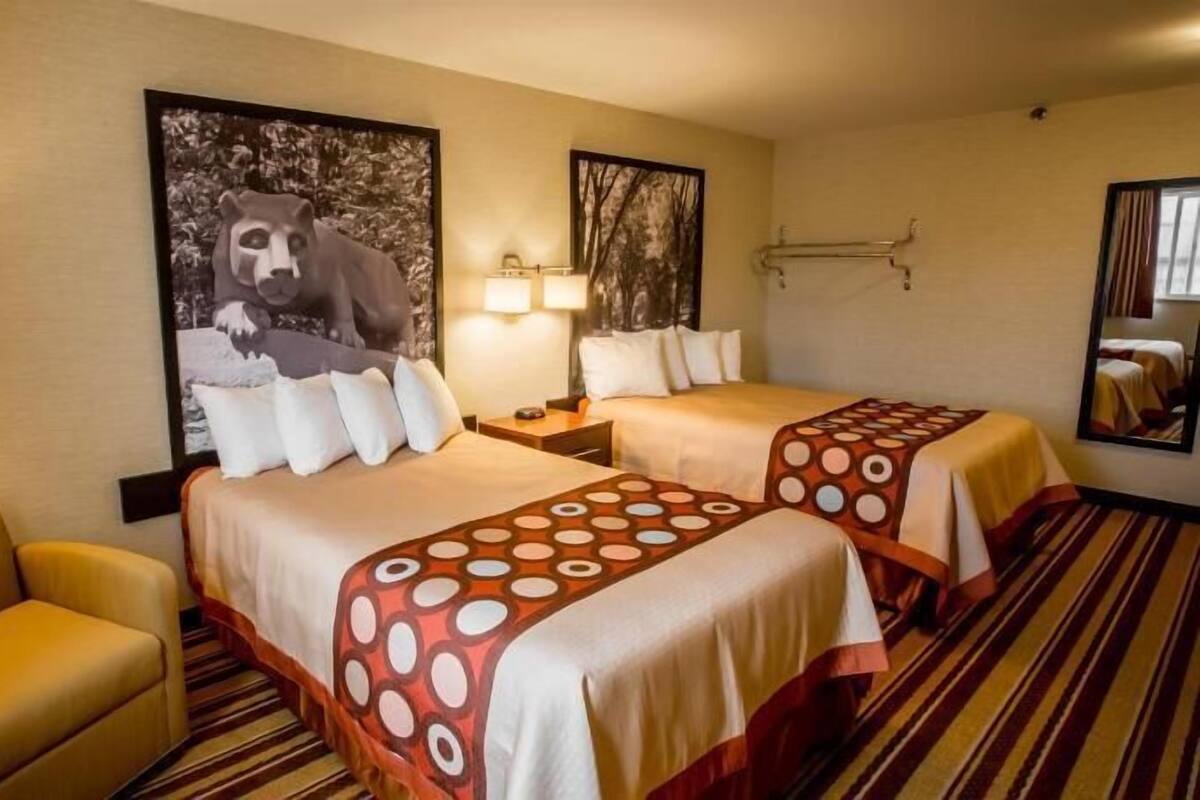 A hotel room with two beds, a sofa, a desk, and a lamp.