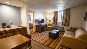 A hotel room with a kitchen area, a sofa, a TV, and a lamp. - Super 8 by Wyndham State College (State College)