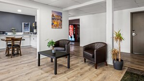 Un hall d’entrée moderne avec un plancher en bois, des fauteuils en cuir, une table basse et une plante en pot.