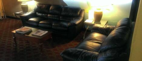 A living room with a black leather sofa, two side tables with lamps, and a small table with a magazine.