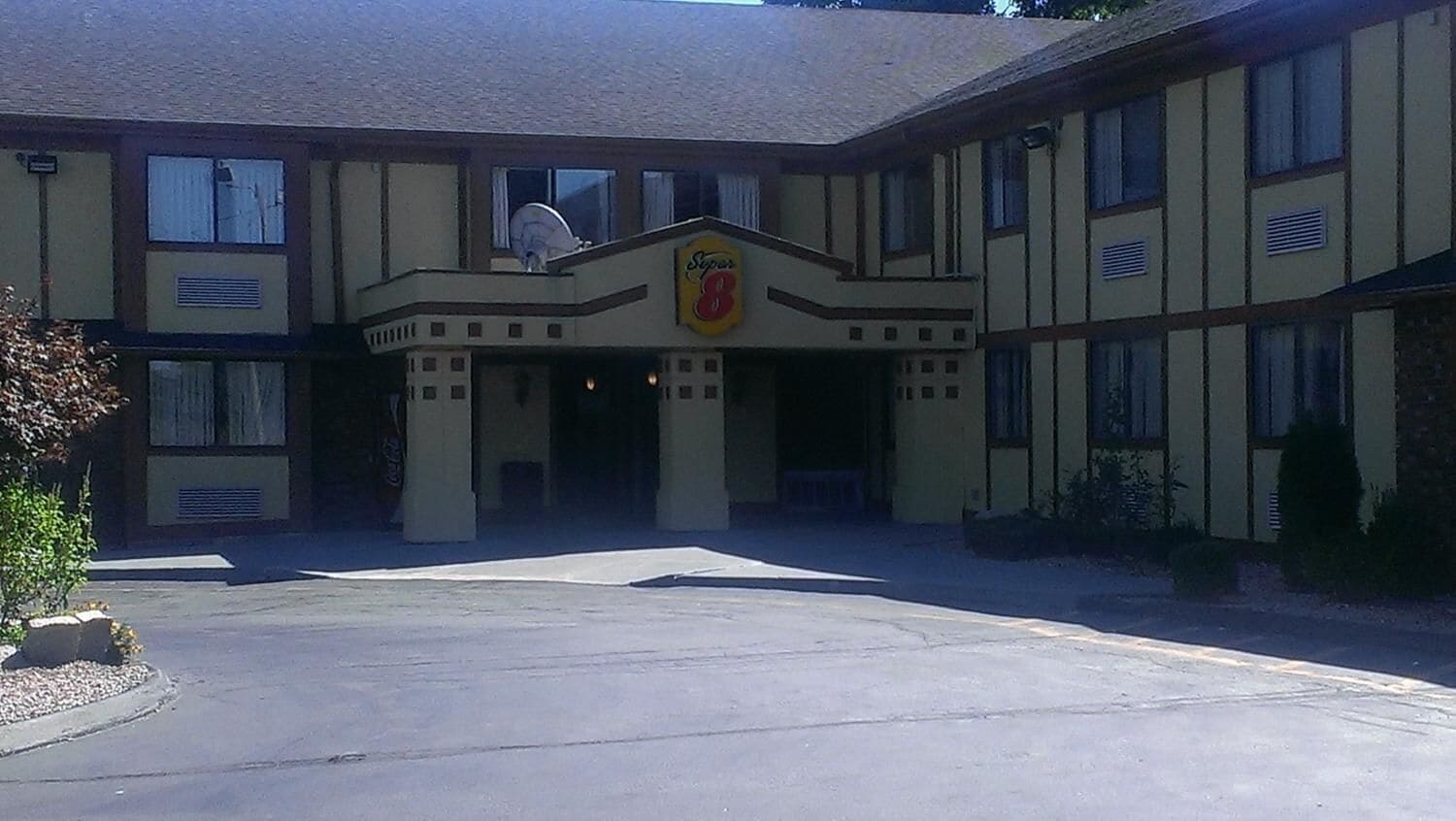 A hotel with a central entrance, a sign above the door, and a satellite dish on the roof.