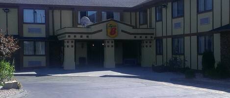 A hotel with a central entrance, a sign above the door, and a satellite dish on the roof.