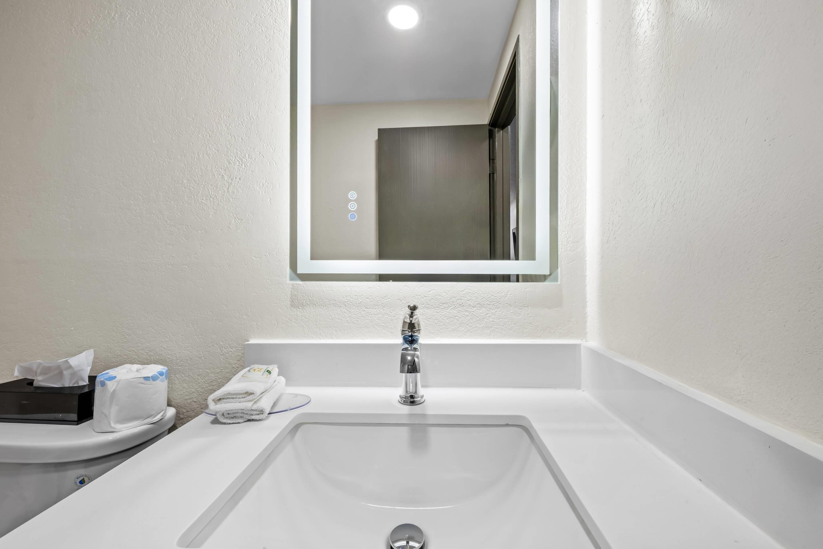 A bathroom with a white sink, a mirror, and a toilet.