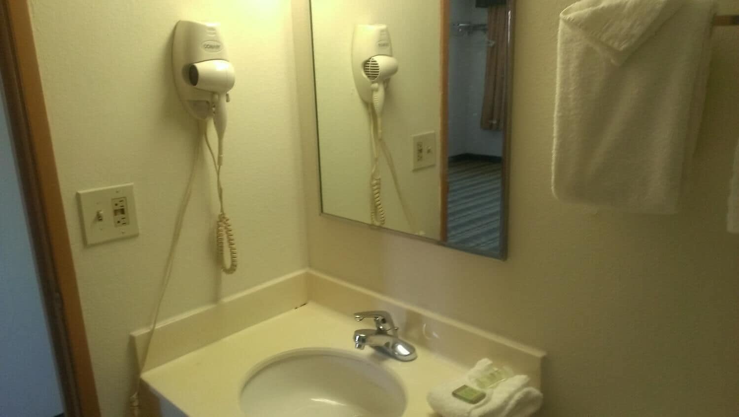 A bathroom with a sink, a hairdryer, and a towel rack.