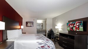 A hotel room with a bed, bedside tables, a desk, a chair, a television, and a mirror. - Red Roof Inn Defuniak Springs (De Funiak Springs)