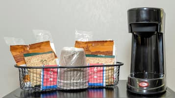 Una cafetera y una cesta con bolsitas de té sobre una mesa.