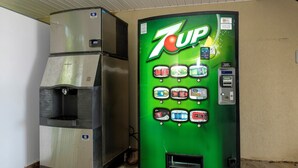 A 7UP vending machine and a stainless steel refrigerator in a room. - Red Roof Inn Defuniak Springs (De Funiak Springs)