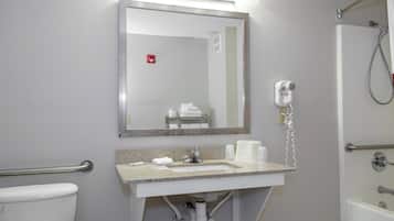 A bathroom with a sink, mirror, towel dispenser, and a hairdryer.