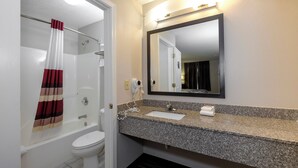 Un baño con ducha, inodoro, lavabo y espejo.