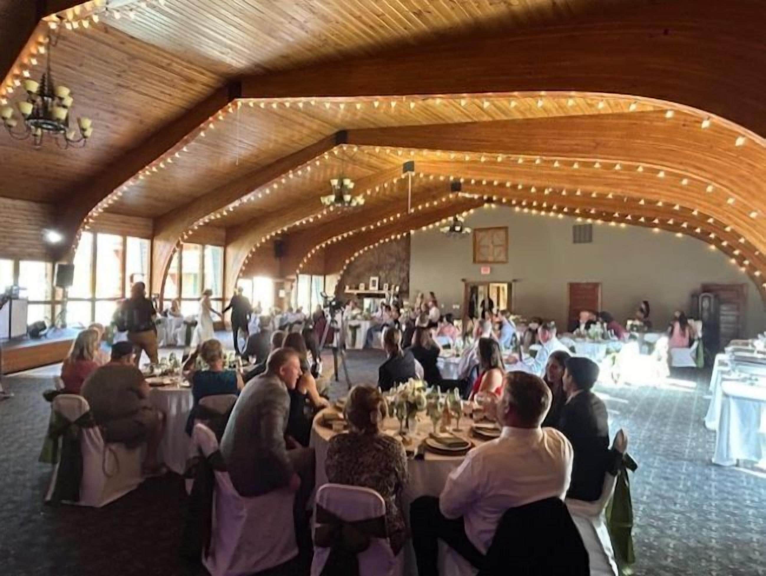 Een ruim evenement in een overdekte ruimte, met ronde tafels en aanwezigen.