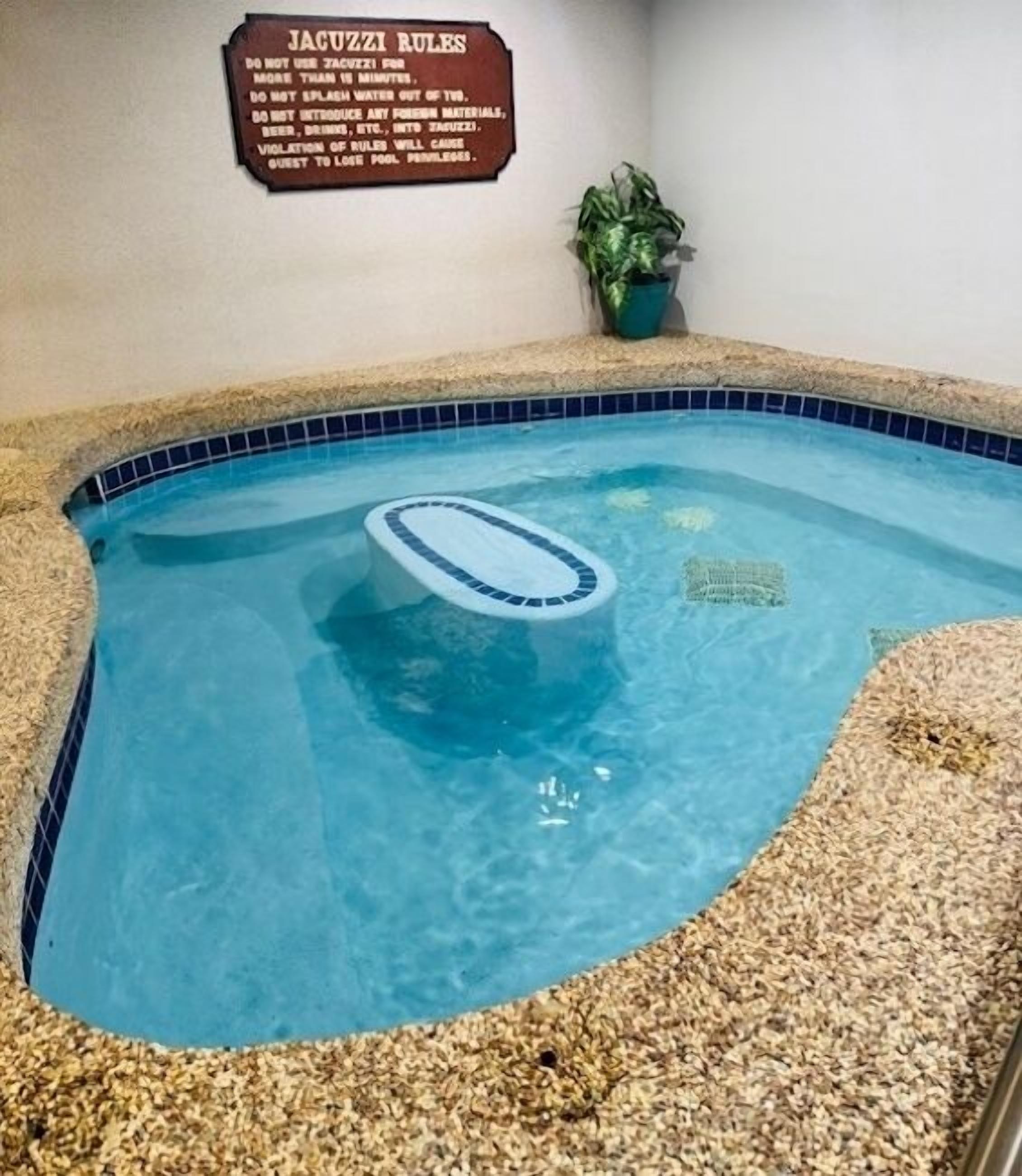 Ein kleiner Innenpool mit einem Schild, das die Jacuzzi-Regeln auflistet.