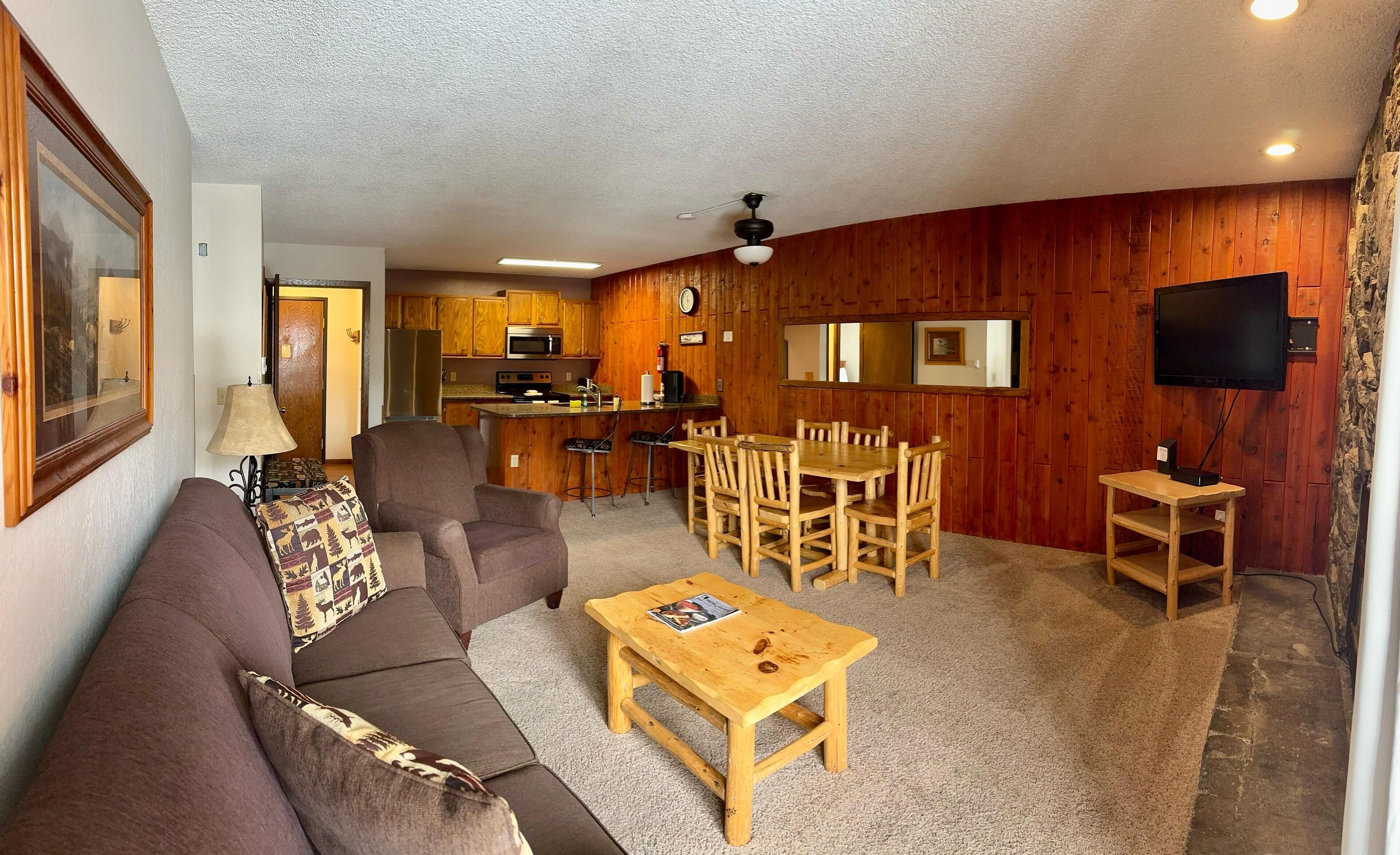 A cozy living room with a sofa, coffee table, and dining area.