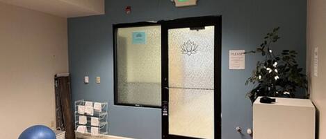 A room with a blue wall, a red carpet, a blue exercise ball, a white reception desk, and an exit sign.