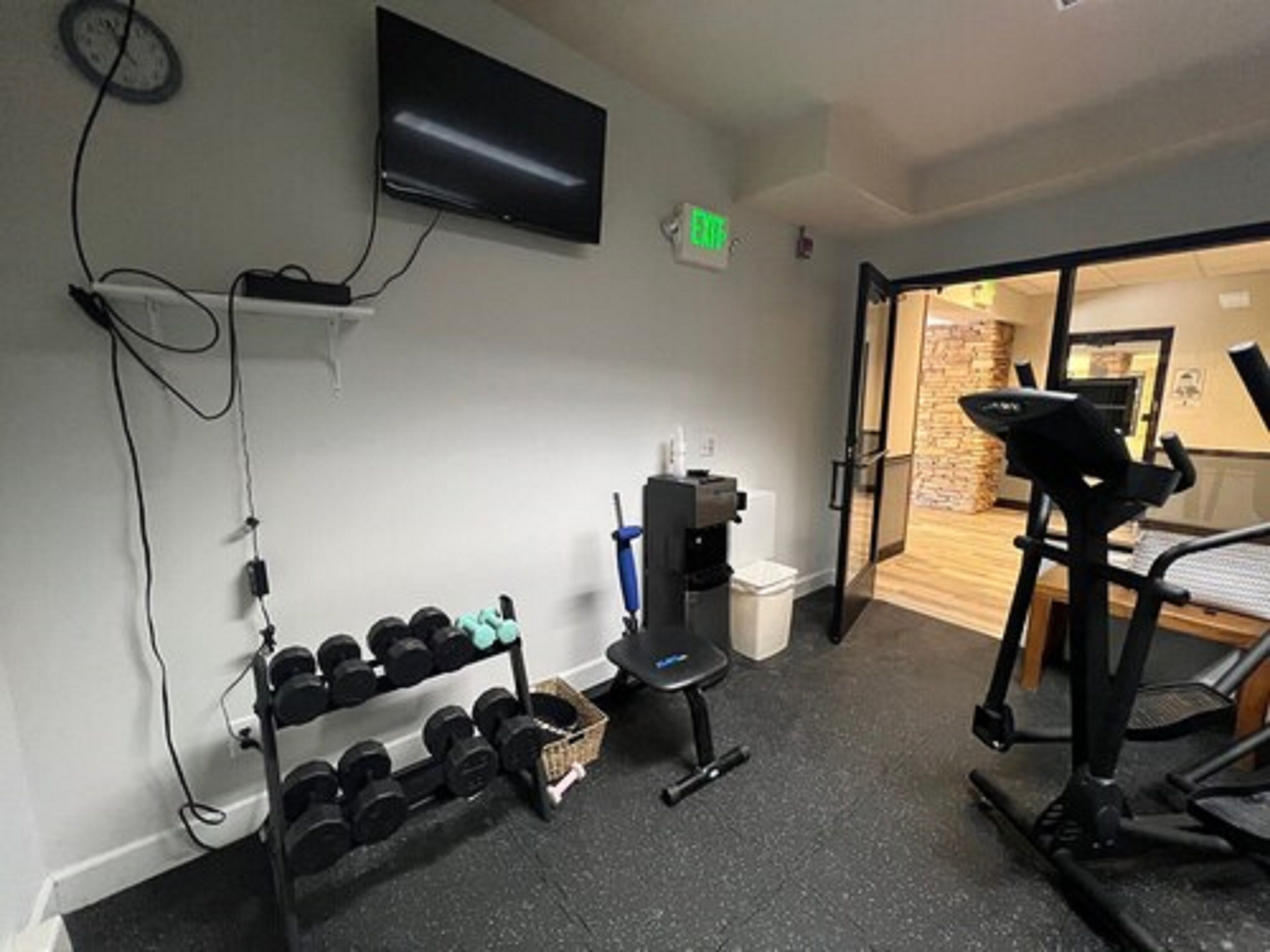 Une salle de sport à domicile équipée d’un tapis de course, d’haltères et d’un vélo d’appartement.