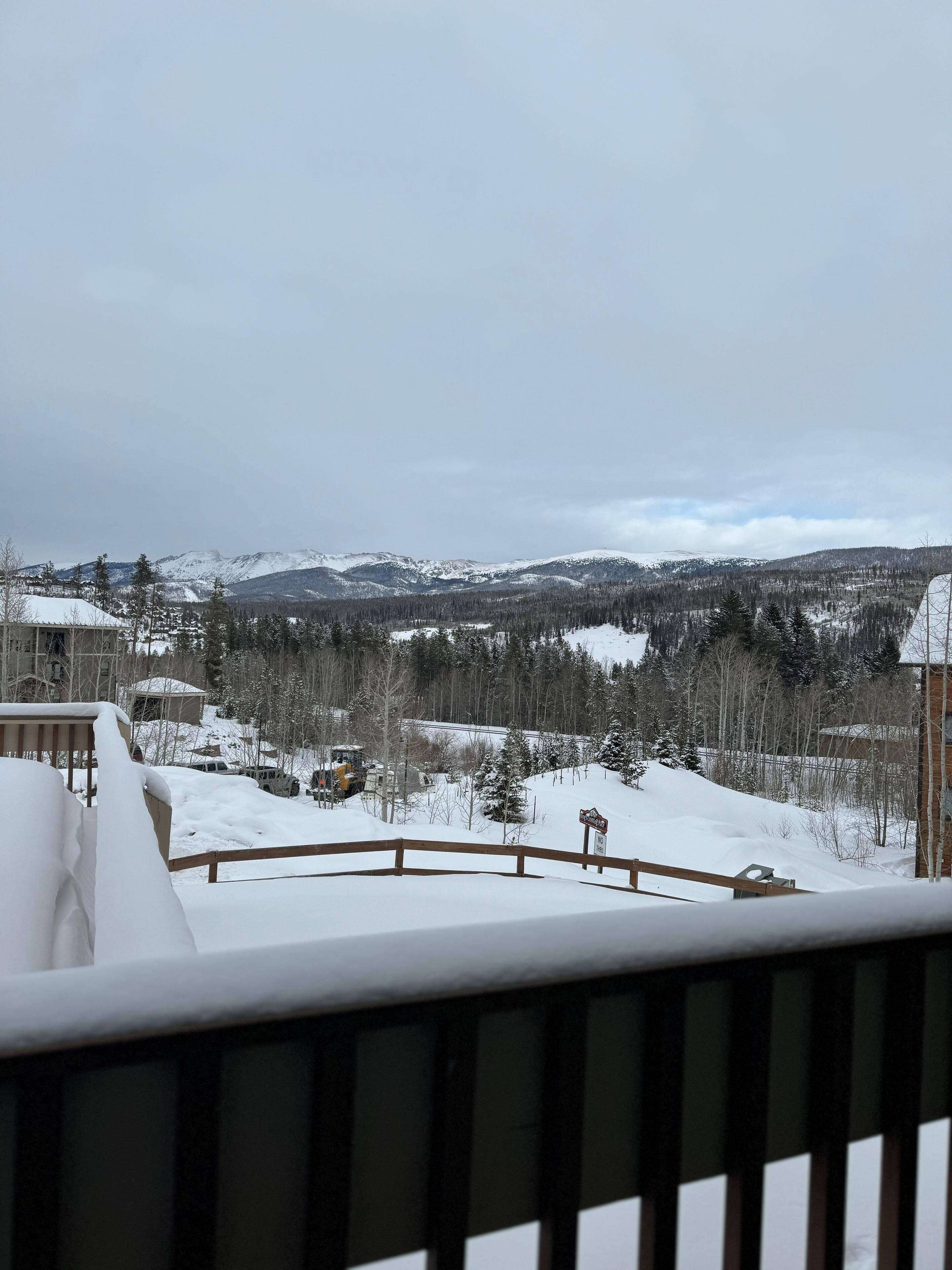 A snowy mountain landscape with a view of a cabin and a snow-covered deck.