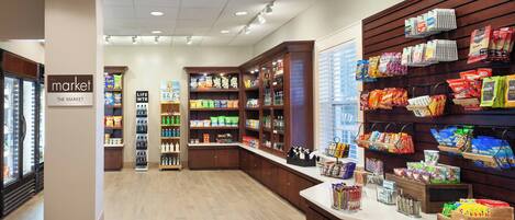A grocery store interior with a variety of products on shelves and counters, including snacks, beverages, and household items.