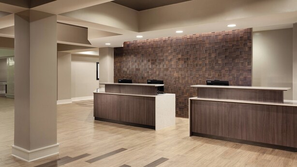 Et receptionområde med moderne design, der inkluderer en receptionsdisk og en væg med et geometrisk mønster.
