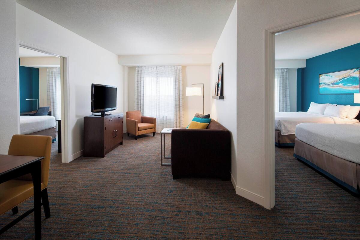 A hotel room with a bed, a TV, a sofa, a desk, and a chair.
