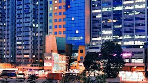 Un hotel moderno a grattacielo, con numerosi piani, ampie finestre e un cartello rosso ben visibile in cima.