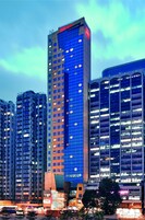 Un hotel moderno de gran altura con numerosas plantas, ventanas amplias y un letrero rojo llamativo en la parte superior.