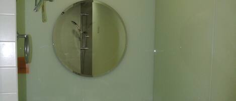Une salle de bain équipée d’un lavabo, d’un miroir, d’un porte-serviettes et d’une poubelle.