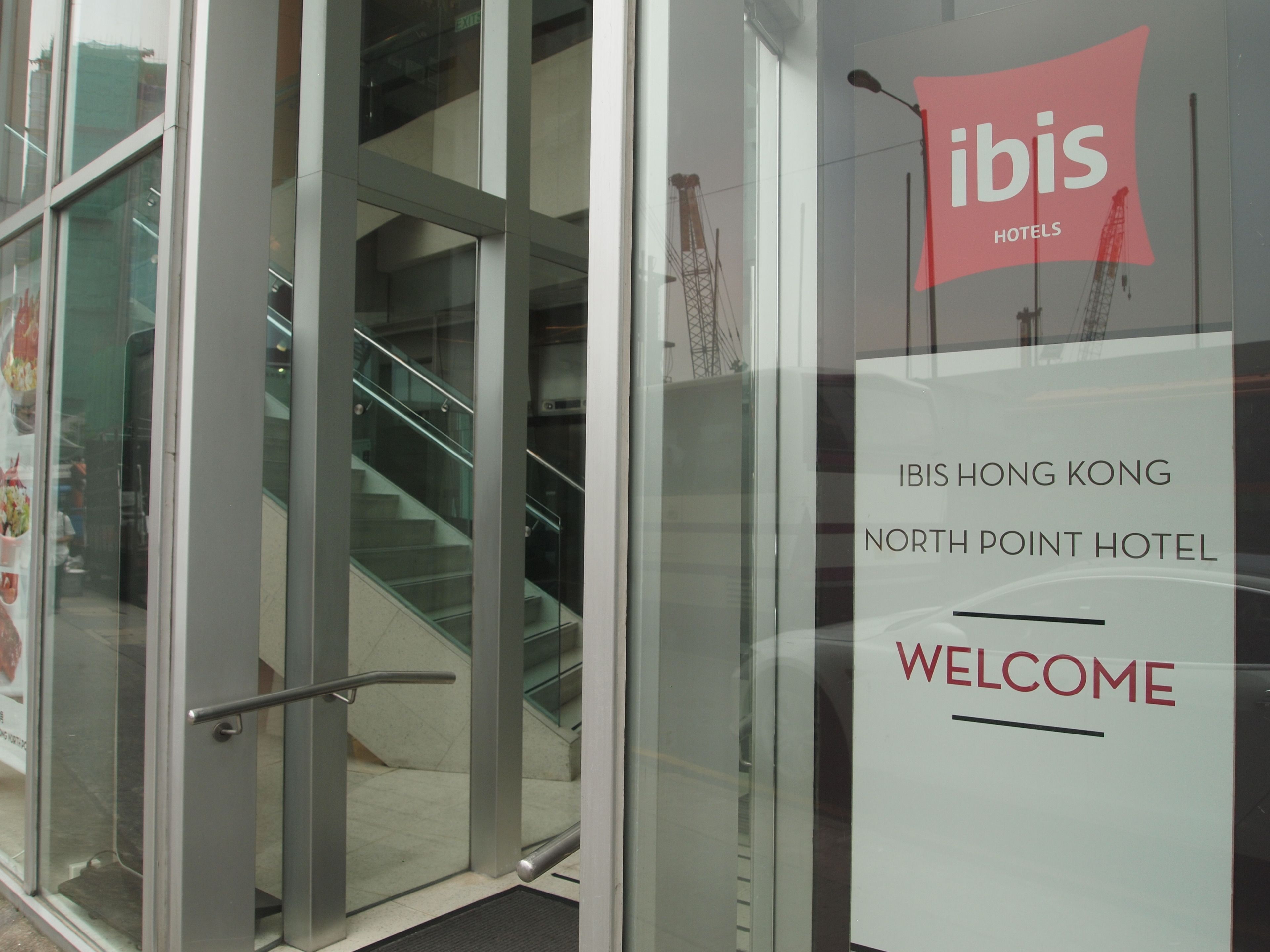 A glass door entrance to the ibis hotels with a staircase leading inside.