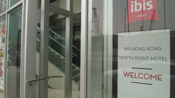 A glass door entrance to the ibis hotels with a staircase leading inside.