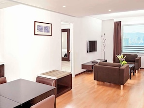 A modern hotel room with a dining area, a sofa set, a flat-screen TV, and a city view. - ibis Hong Kong North Point (Hong Kong)
