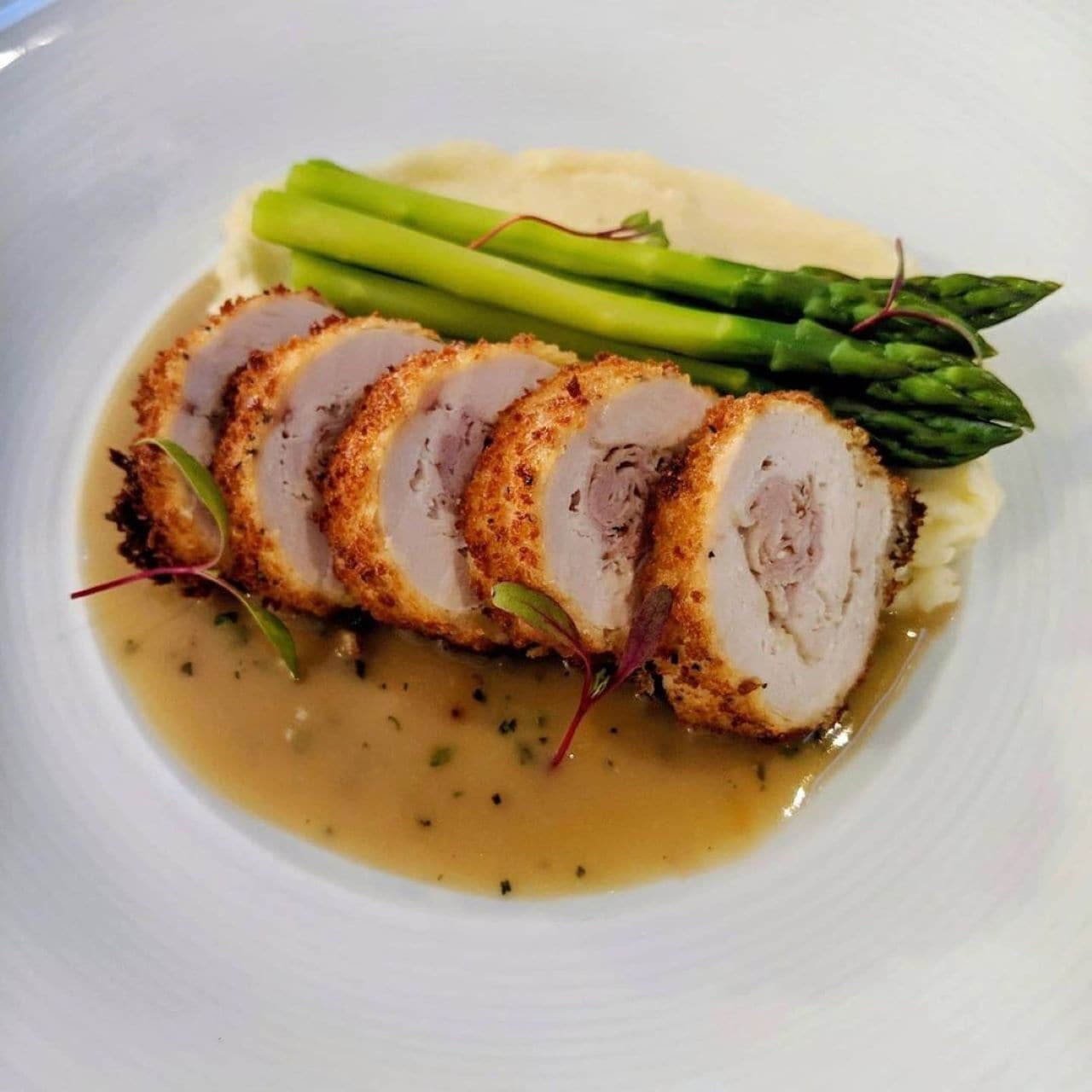 A plate with sliced meat, asparagus, and mashed potatoes.