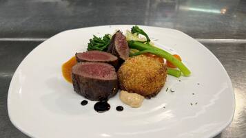 A plate of food with sliced meat, a breaded item, and vegetables.