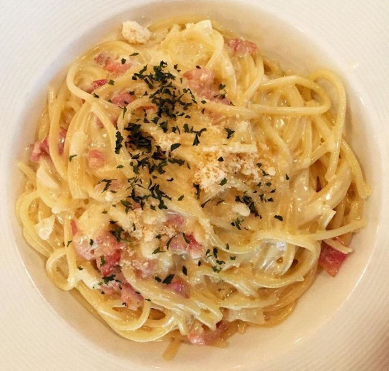 A bowl of pasta with a creamy sauce, garnished with herbs and cheese.