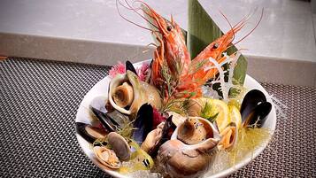 Una bandeja de mariscos con diversos crustáceos y un camarón decorativo sobre una estera trenzada.