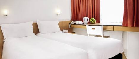 Habitación de hotel con dos camas, un escritorio, una silla, un teléfono y un cuadro en la pared.