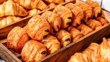 Een houten dienblad met warme, goudbruine croissants.
