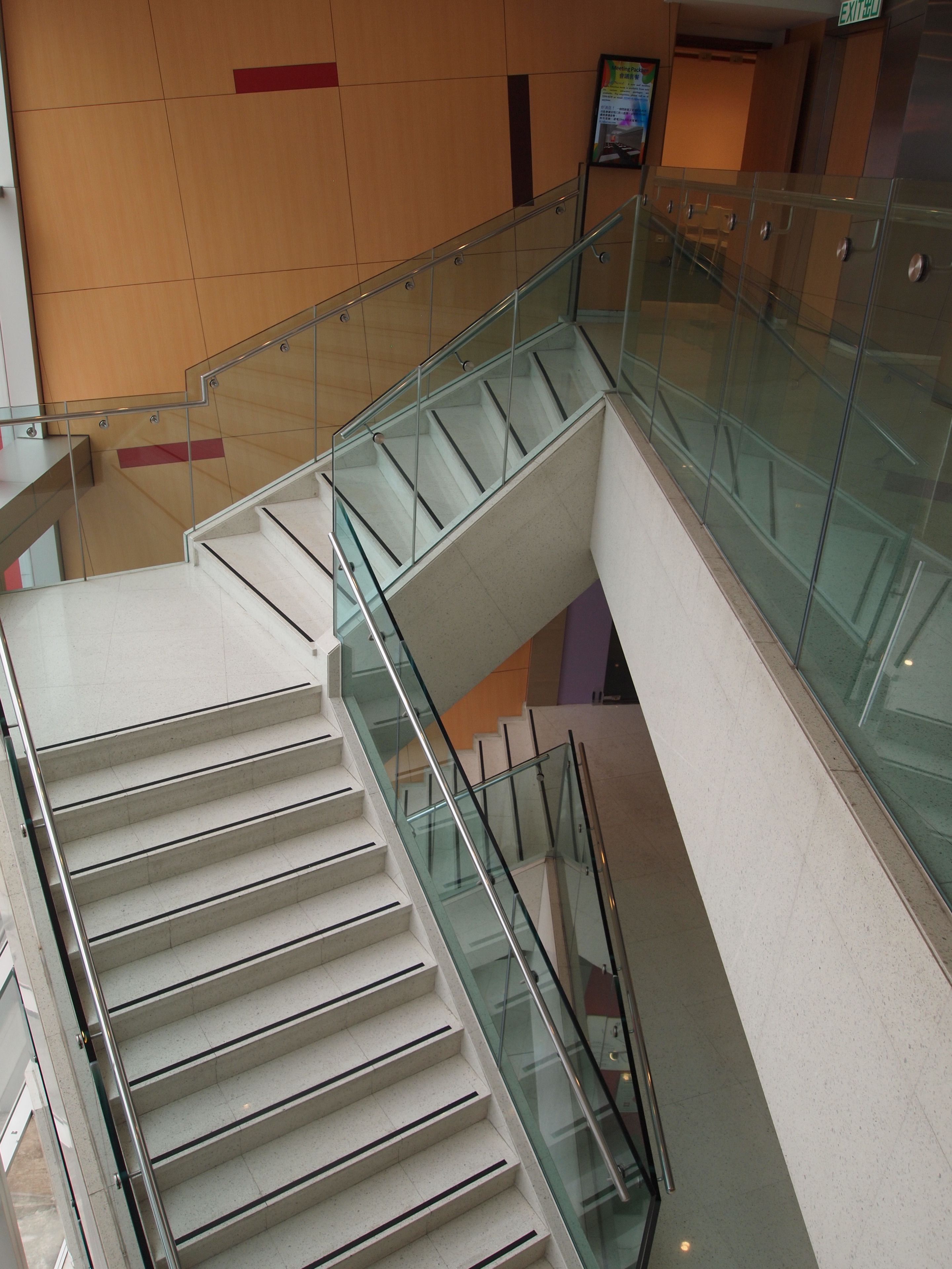 A modern interior with a glass railing staircase connecting two floors.