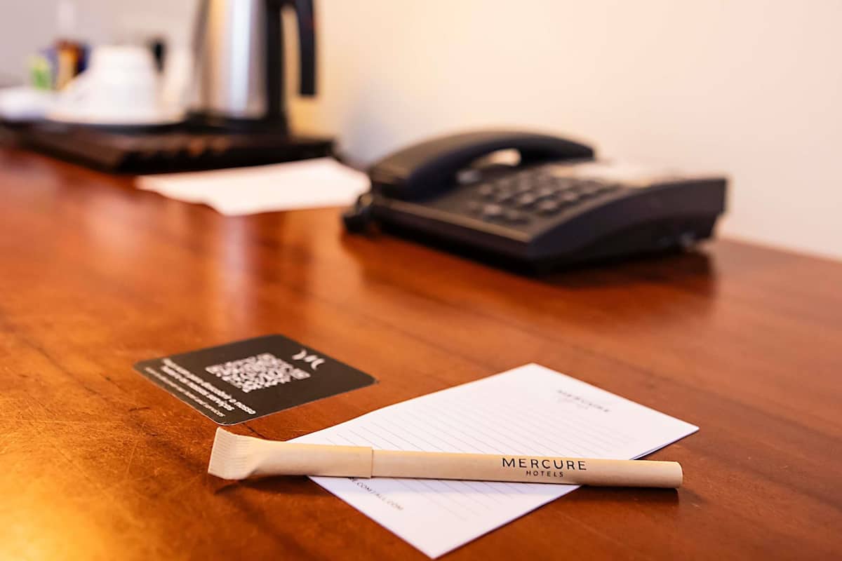 A wooden table with a pen, a business card, and a notepad.