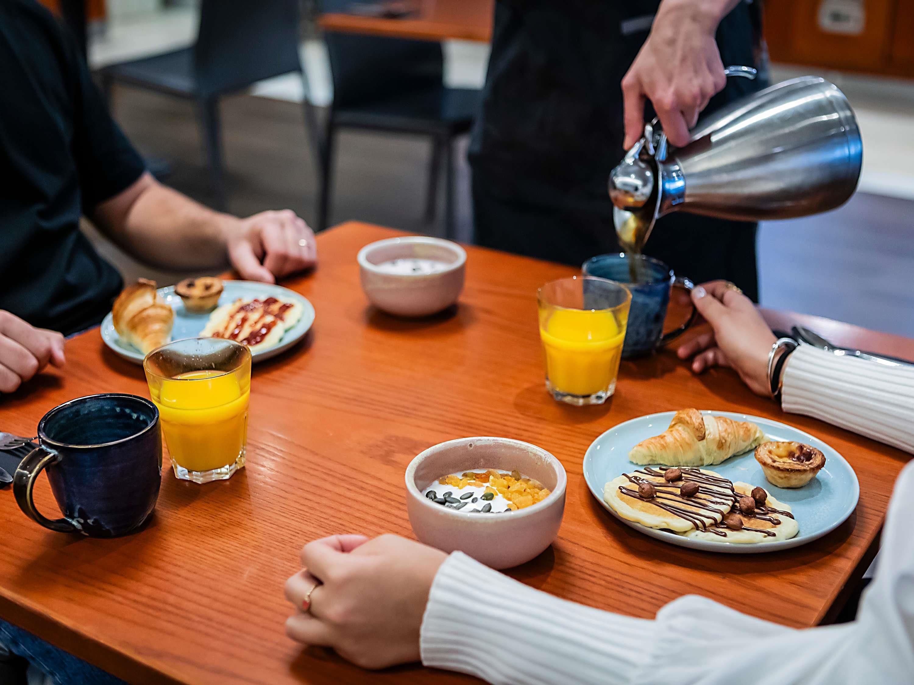 Ein gedeckter Frühstückstisch mit Speisen, einer Kaffeetasse und einem Glas Orangensaft.