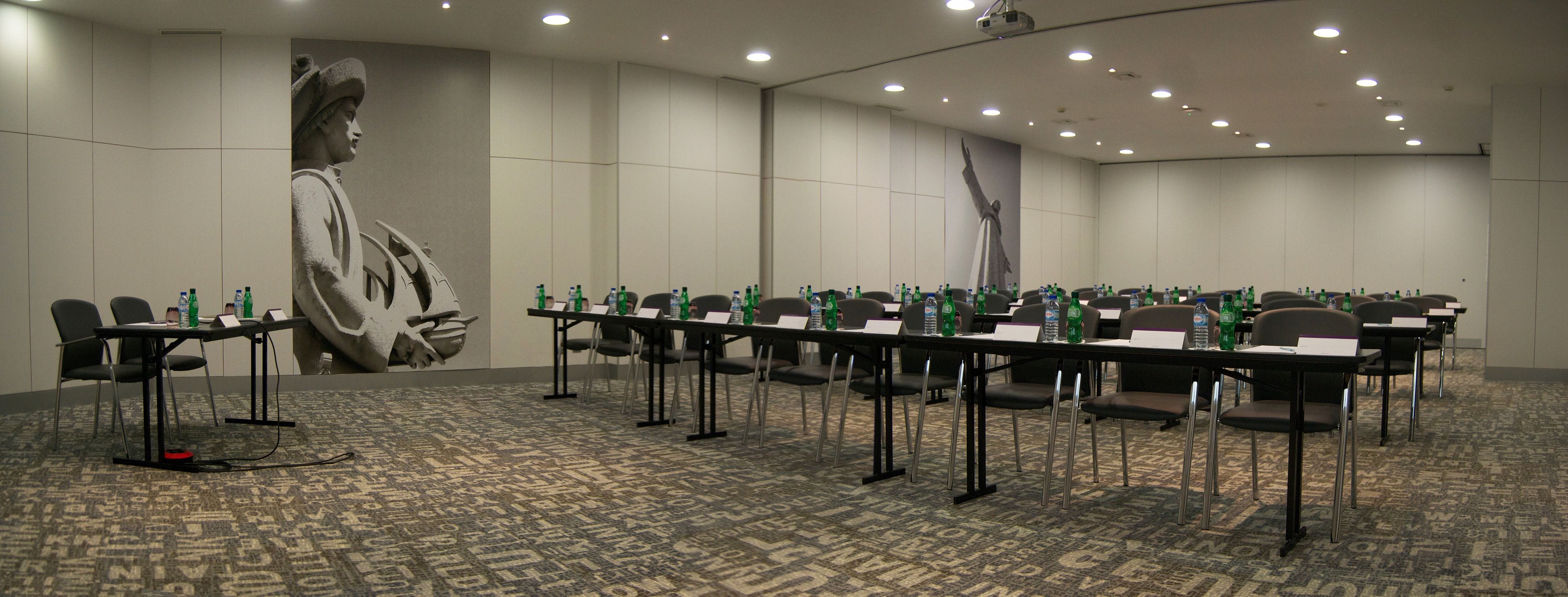 A conference room with multiple tables and chairs, equipped with nameplates and water bottles.