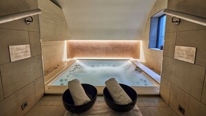 A spa room with a hot tub, two black bowls with towels, caution signs, and a window with a view. - Sofitel London St James (London)