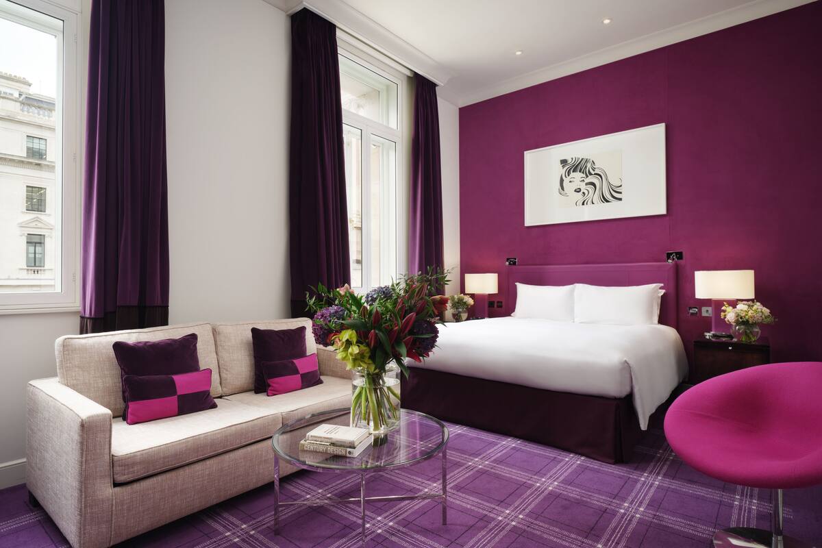 A hotel room with a bed, a sofa, a coffee table, and a chair.