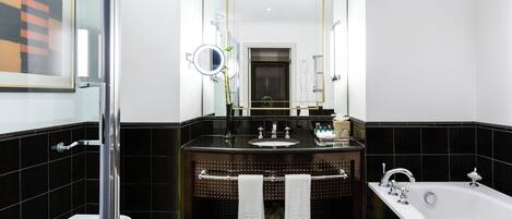 A modern bathroom with a black and white checkered floor, a glass shower enclosure, a white toilet, a black vanity with a mirror, and a white bathtub.
