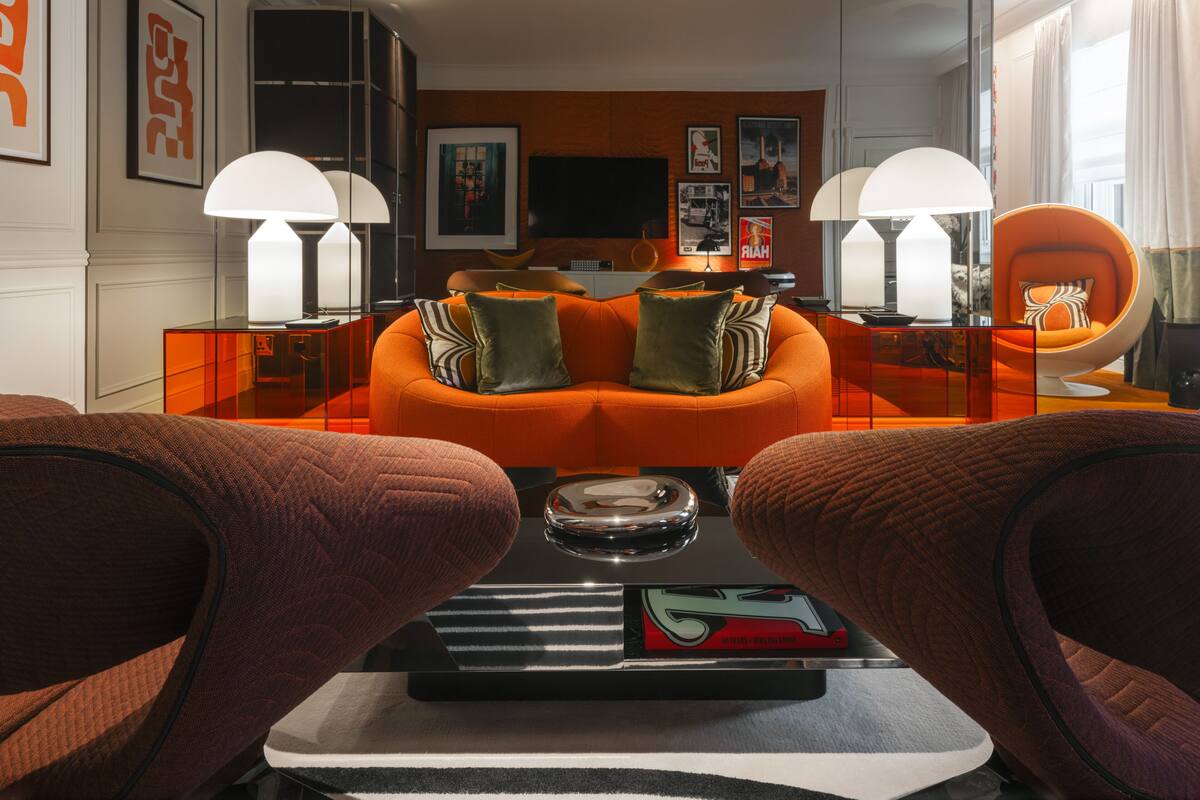 A modern living room with orange sofas, a glass coffee table, and a television.
